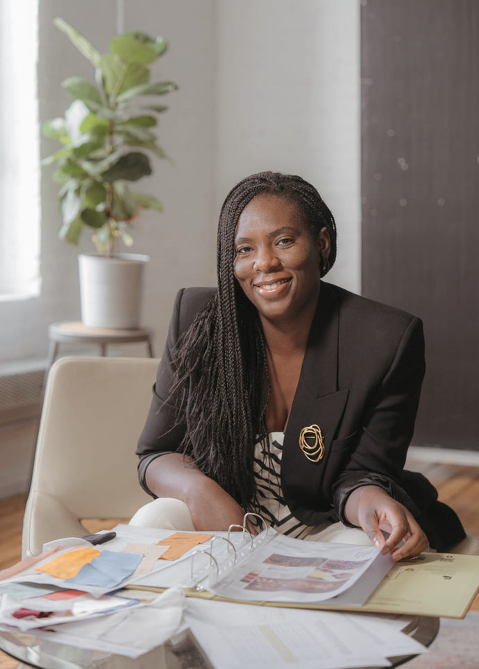 Black woman fashion designer smiling at workspace, representing women led sustainable fashion and ethical leadership